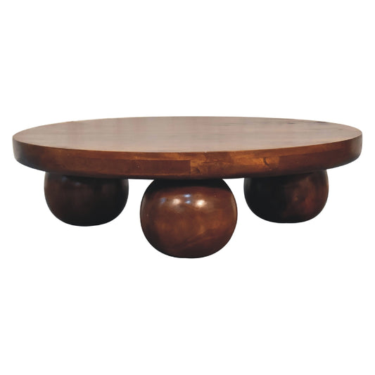 Table basse en manguier massif teinte châtaigne posée sur des pieds boule