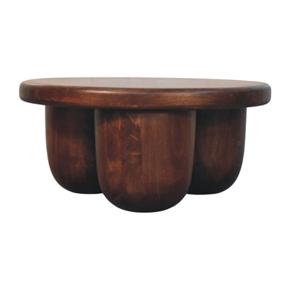 Table basse sculpturale en manguier massif teinte brun rouge, contours adoucis et pieds piliers arrondis